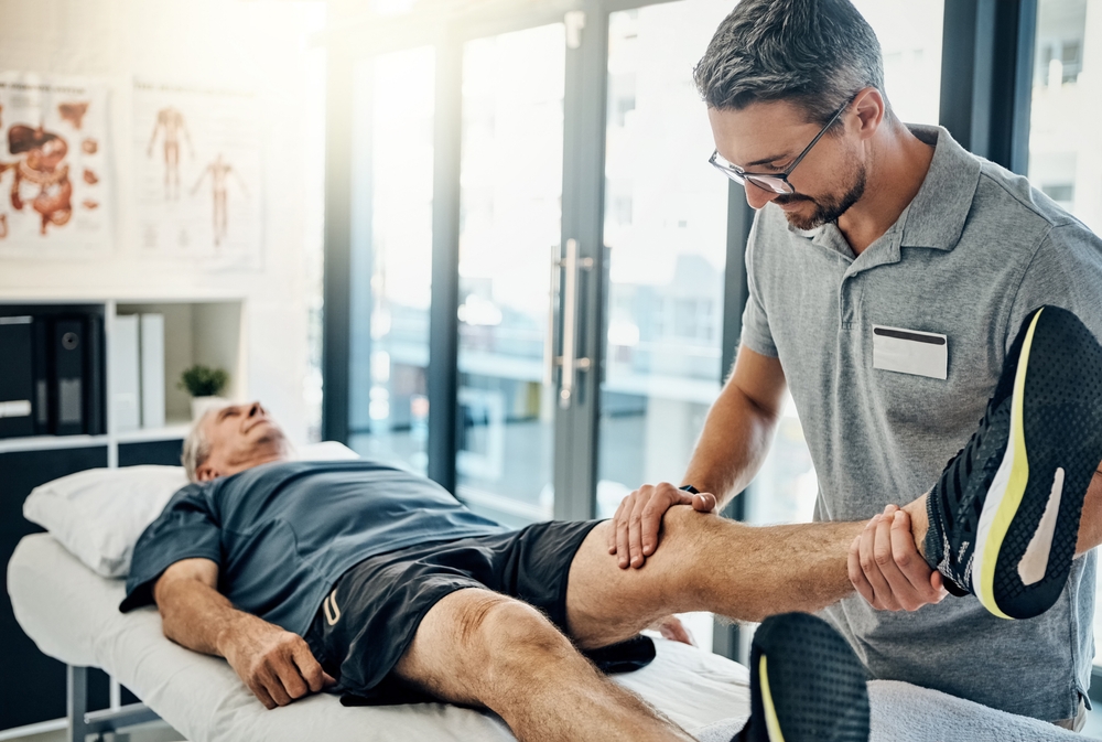 Physiotherapist,,Senior,Man,And,Stretching,Leg,For,Knee,Pain,,Medical