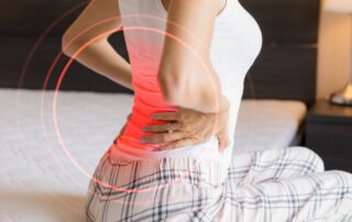 woman sitting in bed supporting her lower back