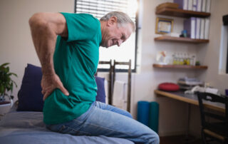 Side,View,Of,Male,Patient,Grimacing,From,Back,Ache,While