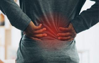 Person holding their lower back with highlighted pain area, representing back discomfort and posture-related strain.