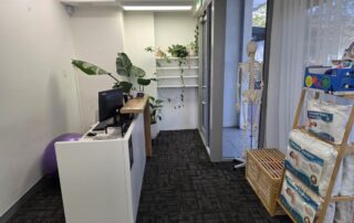 Northbridge Chiropractic reception area in Perth showing the front desk, indoor plants, an anatomical skeleton model near the entrance, and orthopedic pillow products on display.